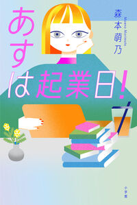 『あすは起業日！』森本萌乃／小学館の書影。オレンジ色の髪の女性が頬杖をつき、ノートパソコンと積み重ねた本、ドリンクが描かれたイラストの表紙